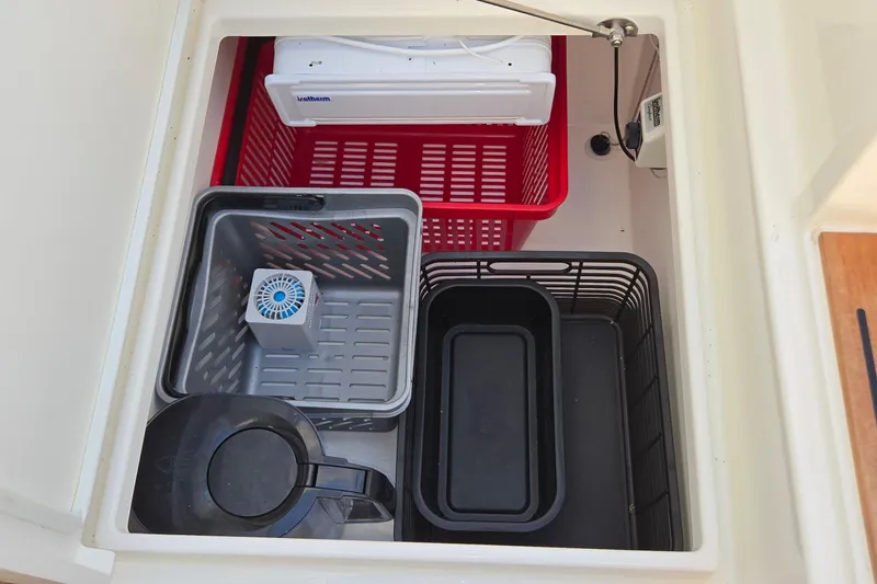 Slide: The Image of Storage compartment with baskets and containers on a 2025 Marex 310 Sun Cruiser. - 56