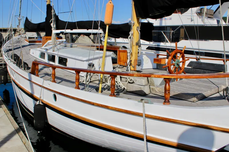 Slide: The Image of Classic 1975 William Garden Porpoise sailboat docked, featuring wooden details and a traditional helm. - 7