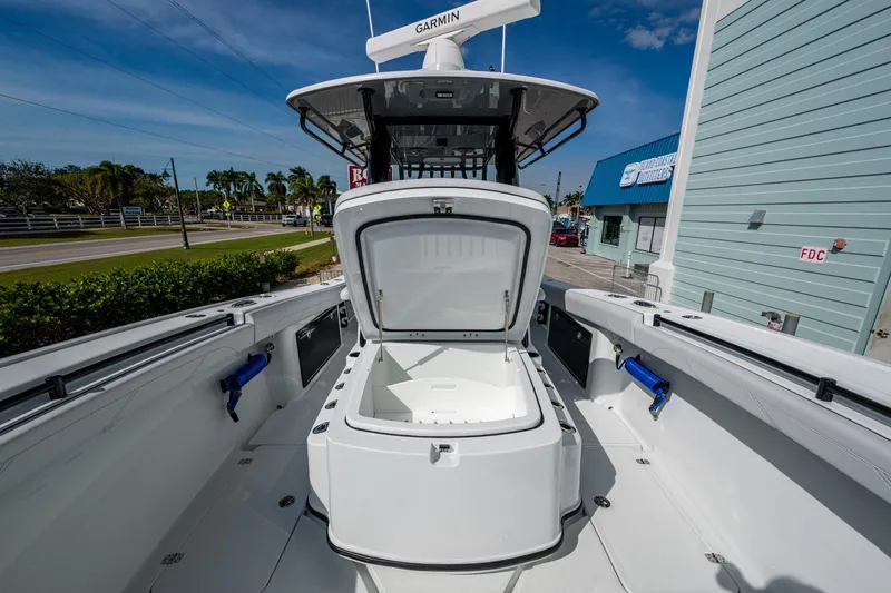 Slide: The Image of 2026 Yellowfin 36 Offshore boat with open storage compartment, docked near coastal buildings. - 21