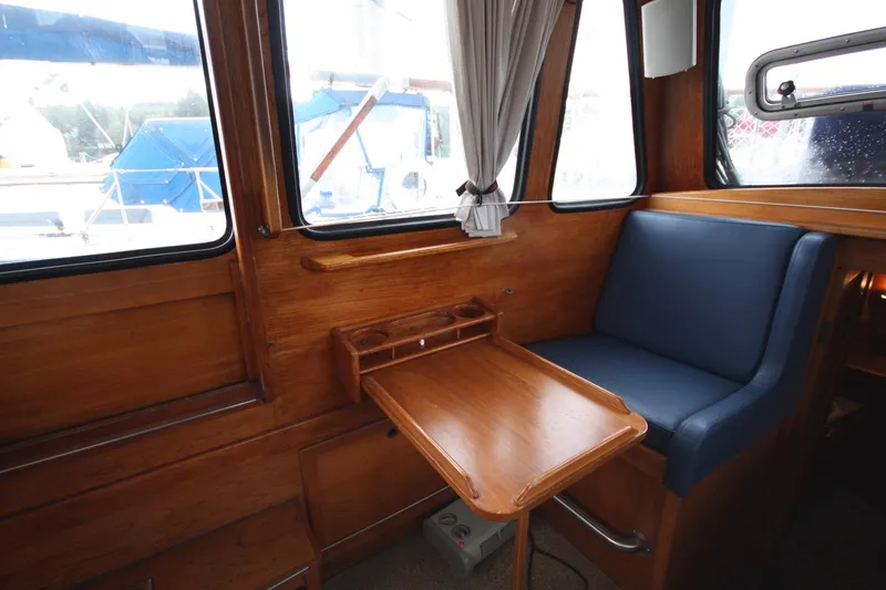 Slide: The Image of Interior of 1984 Nauticat 33 sailboat with wooden table and blue seating. - 13