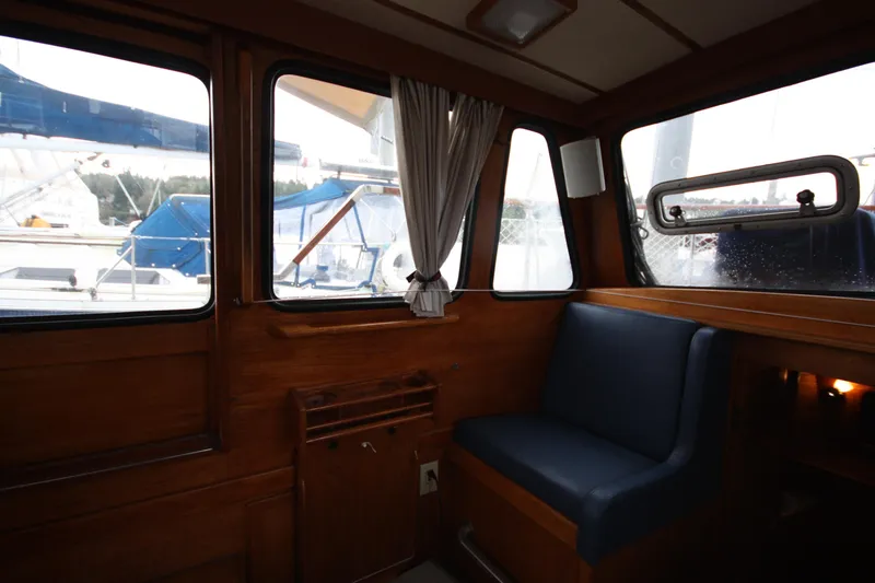 Slide: The Image of Interior of 1984 Nauticat 33 sailboat with wooden paneling and blue cushioned seating. - 14