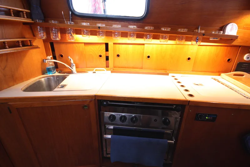 Slide: The Image of 1984 Nauticat 33 yacht kitchen with wooden cabinetry, sink, and stove. - 21