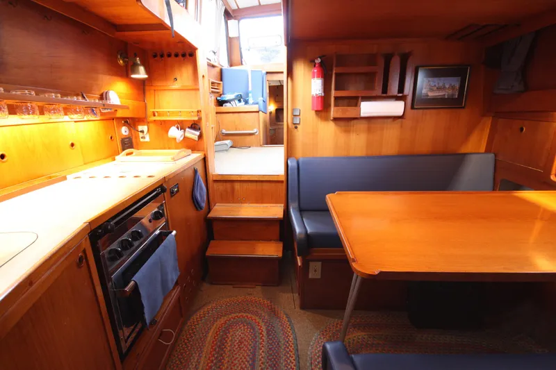 Slide: The Image of Cozy 1984 Nauticat 33 yacht interior with wooden cabinetry and dining area. - 22