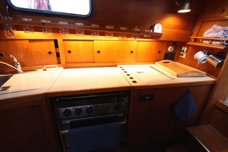 Slide: The Image of 1984 Nauticat 33 yacht kitchen with wooden cabinetry, stove, and sink. - 23