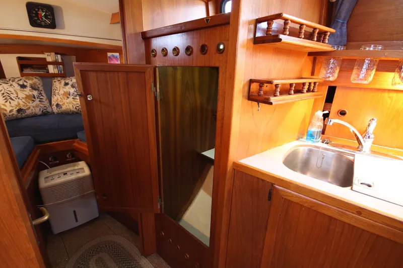 Slide: The Image of 1984 Nauticat 33 interior with wooden cabinetry, sink, and cozy seating area. - 26
