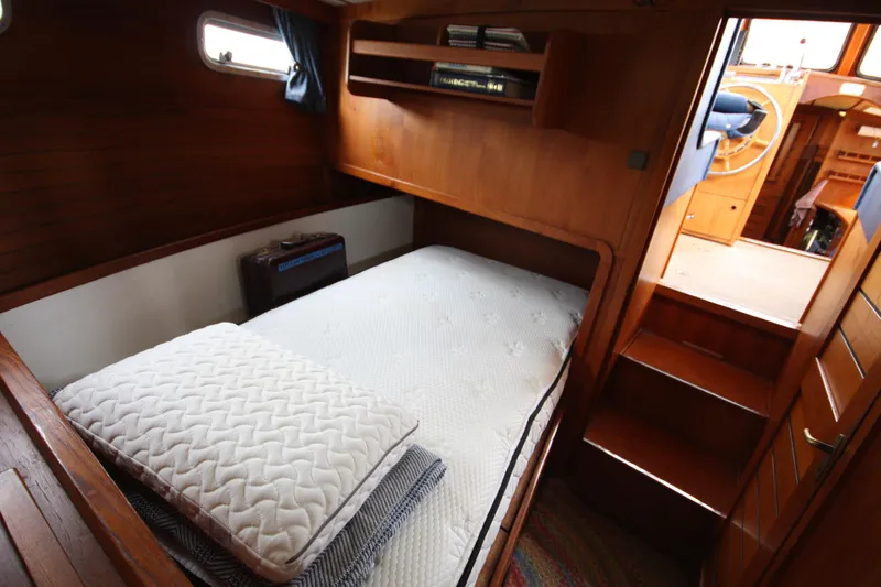 Slide: The Image of Cozy cabin interior of 1984 Nauticat 33 sailboat with wooden furnishings and bedding. - 29