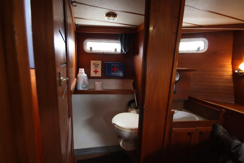 Slide: The Image of 1984 Nauticat 33 yacht bathroom with wooden interior, porthole, and first aid kit. - 31