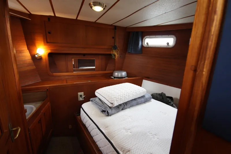 Slide: The Image of Cozy cabin interior of 1984 Nauticat 33 sailboat with wooden paneling and comfortable bedding. - 32