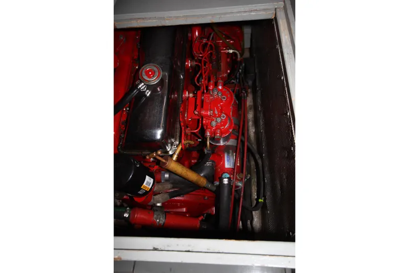 Slide: The Image of Engine compartment of a 1984 Nauticat 33 sailboat, featuring a red engine and components. - 38