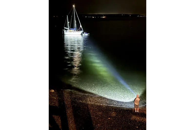 Slide: The Image of Man with flashlight on beach, illuminating Nauticat 33 sailboat at night, 1984 model. - 52