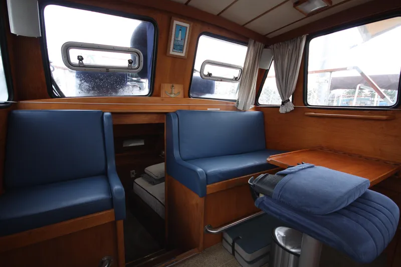 Slide: The Image of 1984 Nauticat 33 interior with blue seating, wooden table, and nautical decor. - 9
