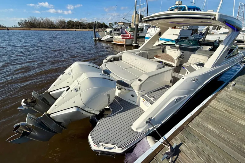 Slide: The Image of 2021 Sea Ray SLX 310 Outboard boat docked, featuring dual Mercury engines. - 13