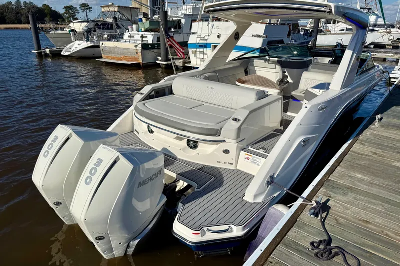 Slide: The Image of 2021 Sea Ray SLX 310 Outboard boat docked, featuring spacious seating and dual Mercury engines. - 14