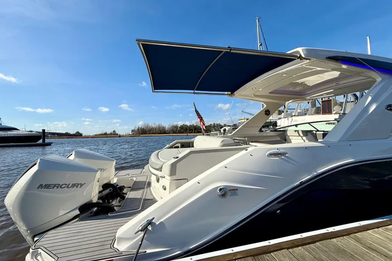 Slide: The Image of 2021 Sea Ray SLX 310 Outboard luxury boat docked at marina, featuring spacious seating. - 16
