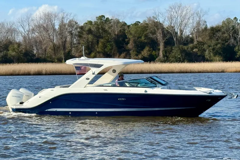 Slide: The Image of 2021 Sea Ray SLX 310 Outboard cruising on a serene lake with American flag. - 2