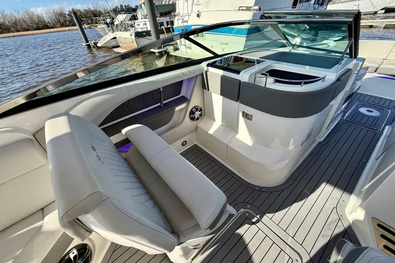 Slide: The Image of 2021 Sea Ray SLX 310 Outboard interior with seating and cabin view at a marina. - 25