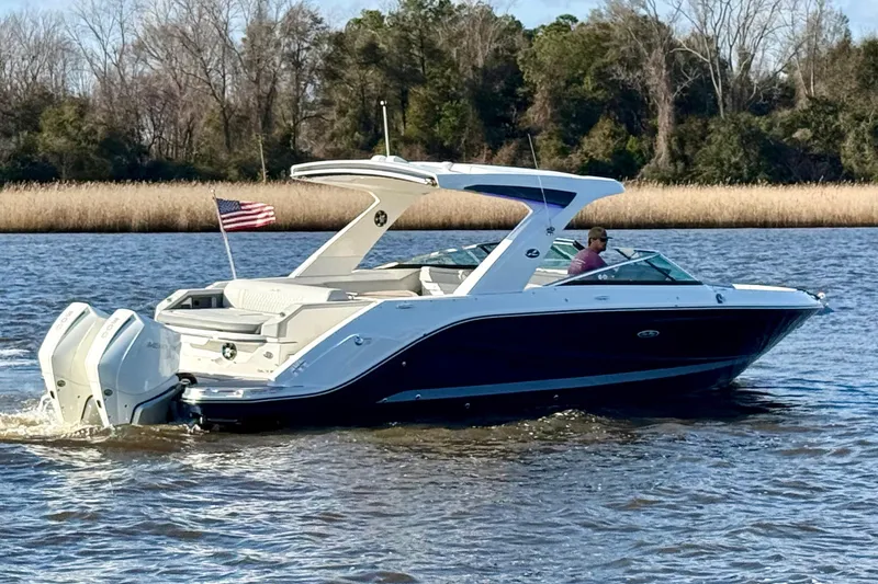 Slide: The Image of 2021 Sea Ray SLX 310 Outboard cruising on a scenic river with American flag. - 3
