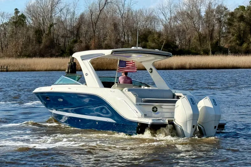 Slide: The Image of 2021 Sea Ray SLX 310 Outboard cruising on a scenic river with American flag. - 6