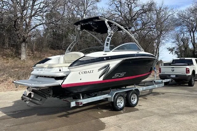 Slide: The Image of 2011 Cobalt 242 WSS boat on trailer, parked near trees and a white truck. - 2