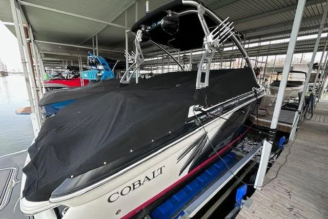 Slide: The Image of 2011 Cobalt 242 WSS boat covered in black tarp, docked in a marina. - 25