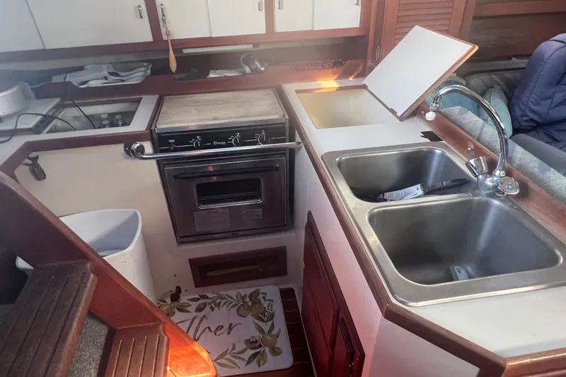 Slide: The Image of 1989 Catalina 36 yacht kitchen with dual sinks, stove, and wooden cabinetry. - 28