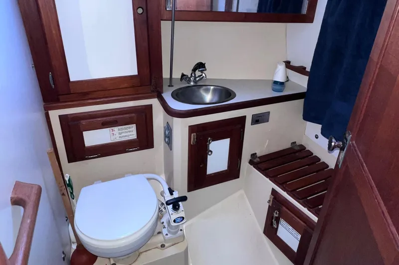 Slide: The Image of 1989 Catalina 36 yacht bathroom with wooden cabinets, sink, and marine toilet. - 48