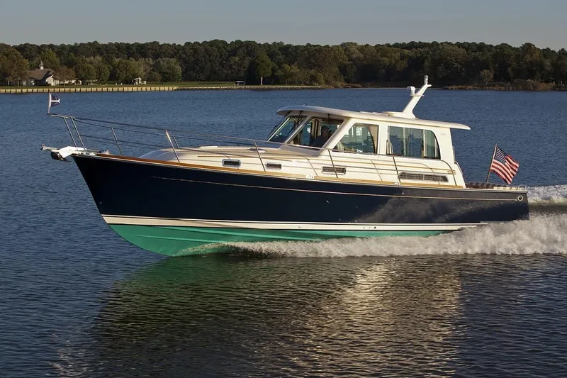 The Image of 2011 Sabre 42 Salon Express yacht docked in a marina, surrounded by water and trees. - 0