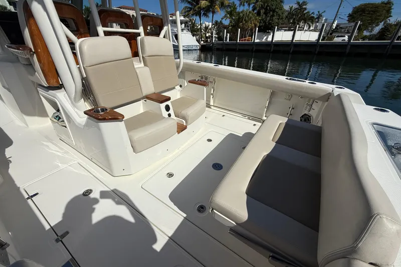 Slide: The Image of 2023 Boston Whaler 360 Outrage boat interior with beige seating and wood accents. - 20