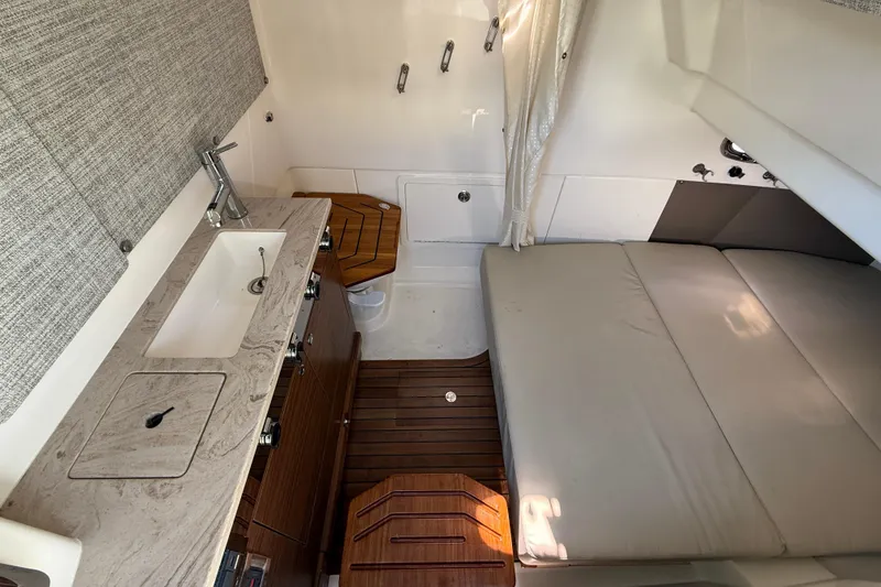 Slide: The Image of 2023 Boston Whaler 360 Outrage cabin interior with sink, countertop, and cushioned seating. - 25