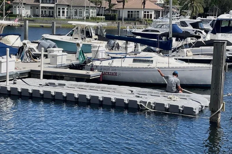Slide: The Image of Man sitting on dock near Yamaha Boats SX220, 2023 model, in a marina setting. - 15