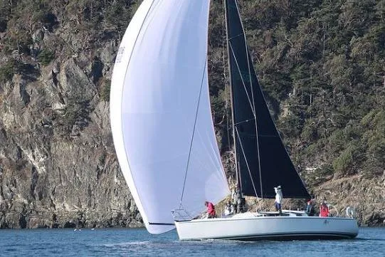 The Image of Sailing yacht Farr 395 (2001) with white and black sails near rocky coastline. - 0