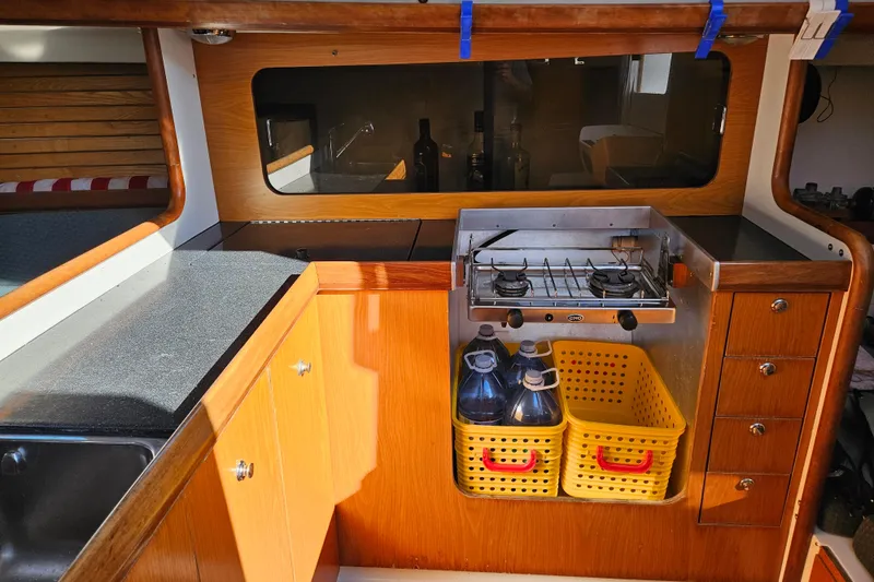 Slide: The Image of Galley kitchen in 2001 Farr 395 sailboat with stove, storage, and countertop. - 13