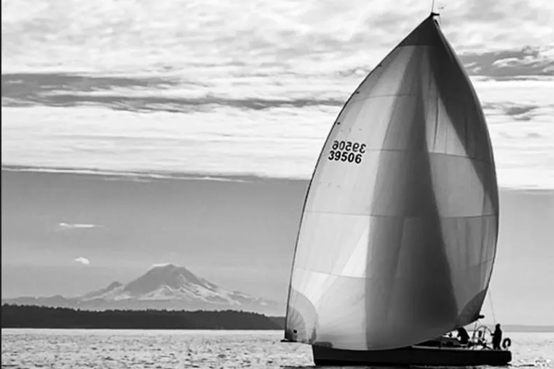 Slide: The Image of Sailboat Farr 395 (2001) with spinnaker, mountain backdrop, and cloudy sky. - 23