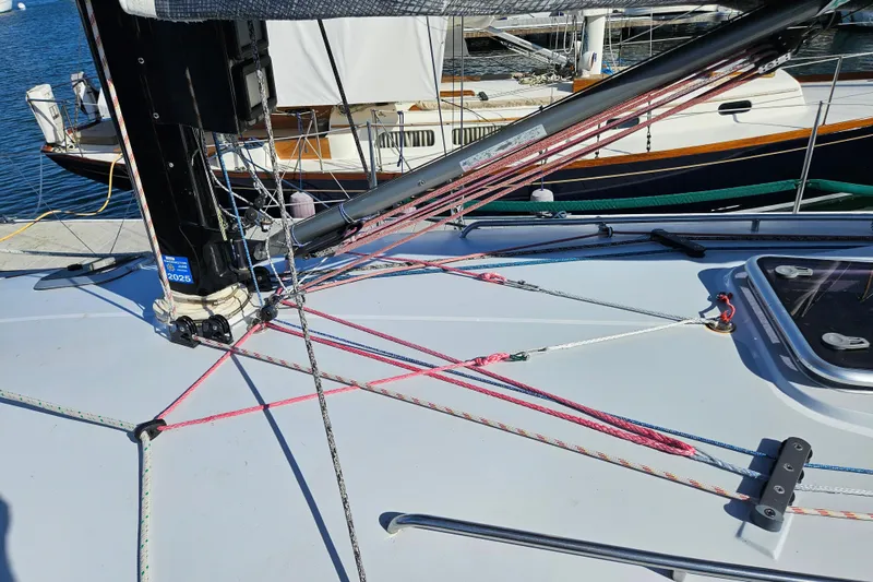 Slide: The Image of Sailboat deck of a 2001 Farr 395 with colorful rigging and docked boats in the background. - 9