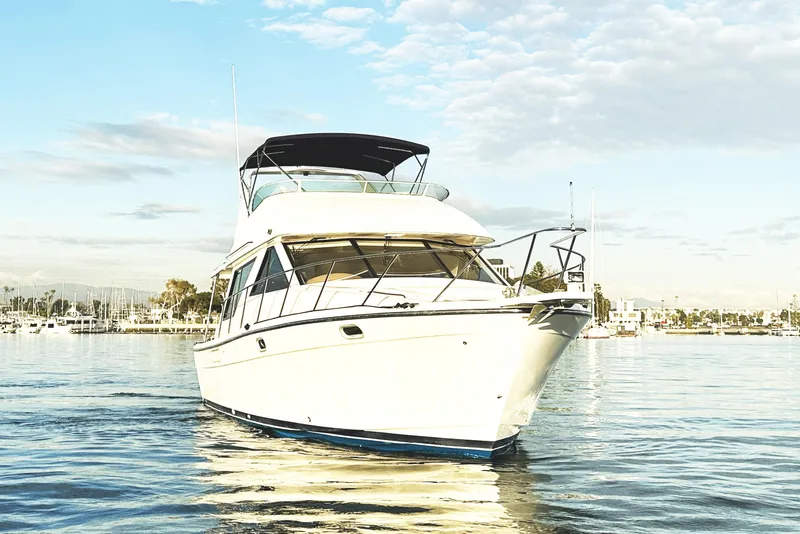Slide: The Image of 2002 Bayliner 3988 Command Bridge Motoryacht on calm water under a cloudy sky. - 14
