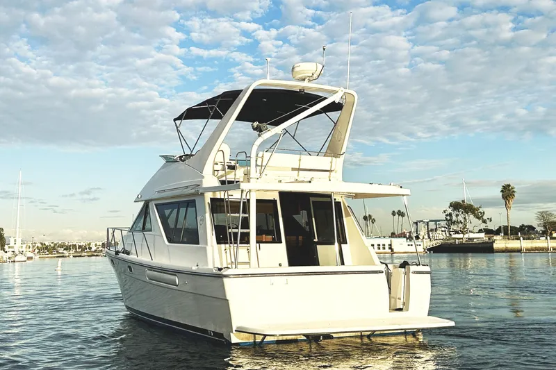 Slide: The Image of 2002 Bayliner 3988 Command Bridge Motoryacht on calm water, under a partly cloudy sky. - 4