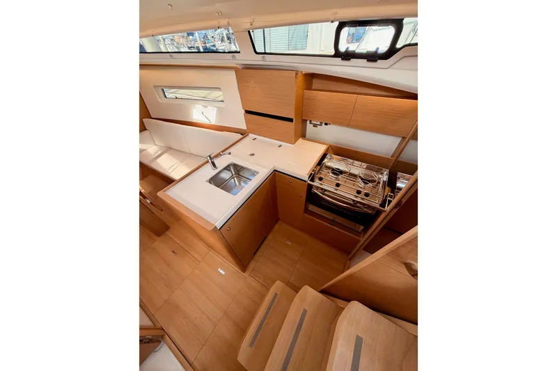 Slide: The Image of Modern kitchen interior of 2025 Jeanneau Sun Odyssey 350 yacht, featuring wood cabinetry and compact design. - 53