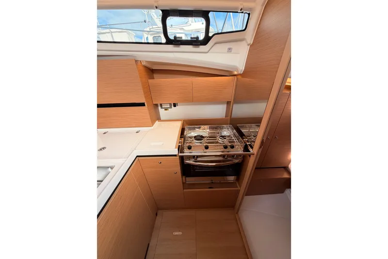 Slide: The Image of Modern kitchen interior of 2025 Jeanneau Sun Odyssey 350 yacht, featuring sleek wood cabinetry. - 56