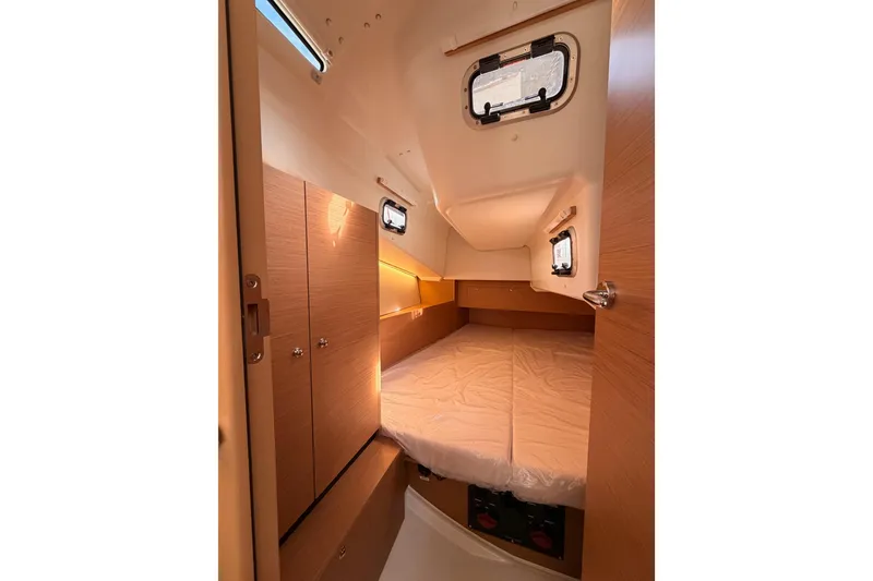 Slide: The Image of Cozy cabin interior of 2025 Jeanneau Sun Odyssey 350 sailboat, featuring wood finishes and portholes. - 61