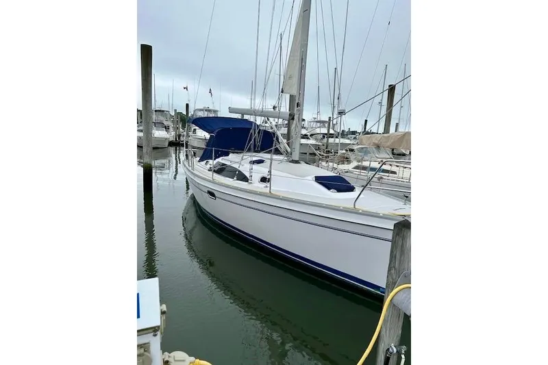Slide: The Image of 2015 Catalina 315 sailboat docked in a marina, featuring a sleek white hull. - 2