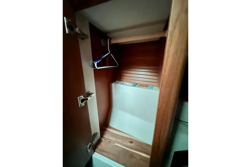 Slide: The Image of Wooden closet interior in a 2015 Catalina 315 sailboat, featuring hangers and storage space. - 23