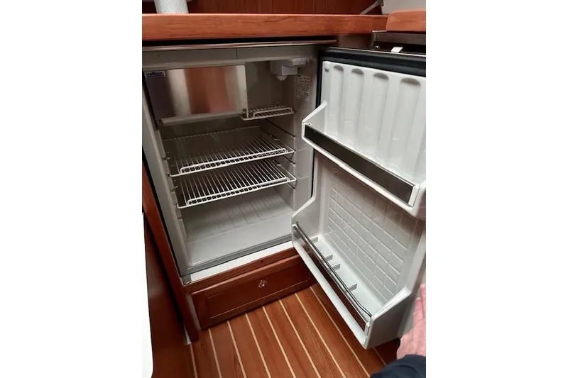 Slide: The Image of Open refrigerator inside a 2015 Catalina 315 yacht, featuring wire shelves and door storage. - 32