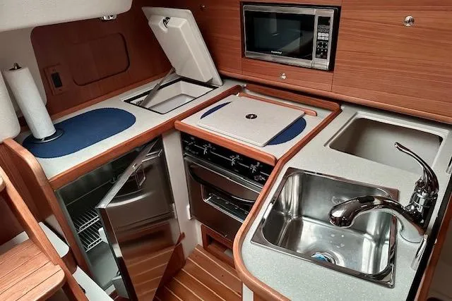 Slide: The Image of 2015 Catalina 315 yacht kitchen with sink, stove, microwave, and refrigerator. - 6