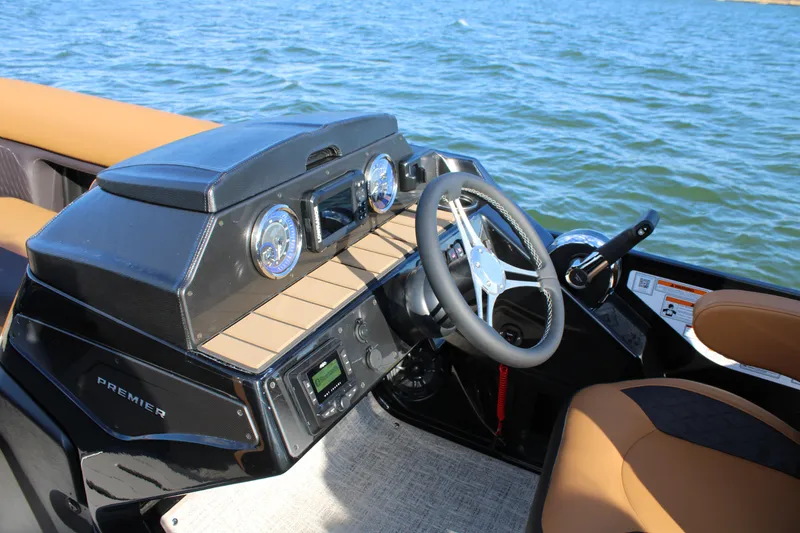 Slide: The Image of 2026 Premier 230 SunSation RF boat dashboard with steering wheel and controls on water. - 11