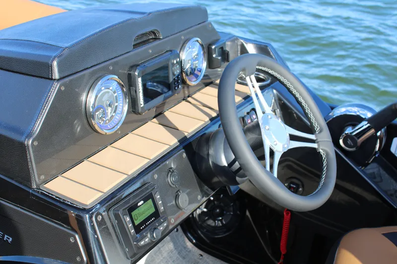 Slide: The Image of 2026 Premier 230 SunSation RF boat dashboard with steering wheel and gauges on water. - 12