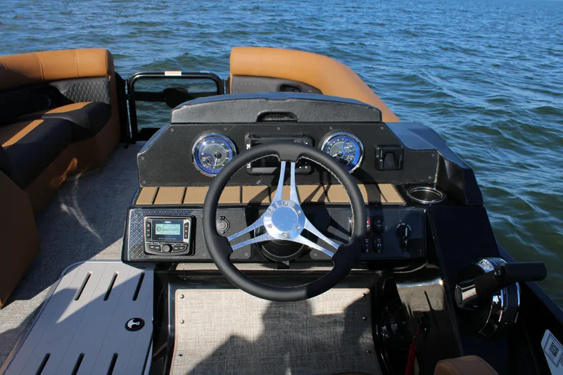 Slide: The Image of 2026 Premier 230 SunSation RF boat dashboard with steering wheel on open water. - 13