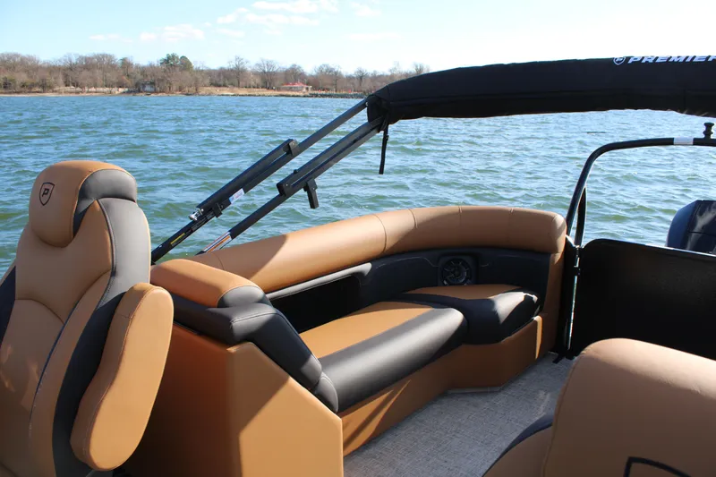 Slide: The Image of 2026 Premier 230 SunSation RF pontoon boat interior with tan seating on a lake. - 16