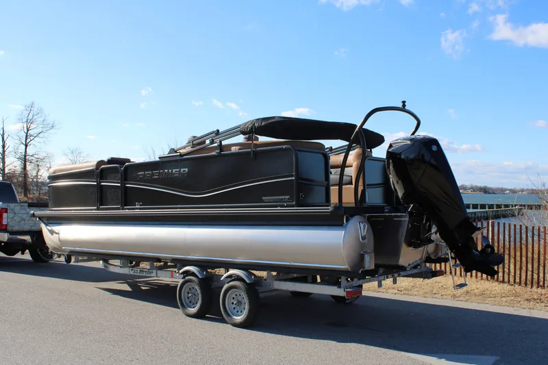 Slide: The Image of 2026 Premier 230 SunSation RF pontoon boat on trailer, parked by a lakeside road. - 3