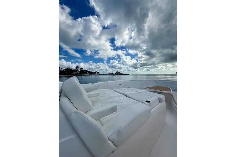 Slide: The Image of Luxurious seating on 2022 Intrepid 407 Nomad SE boat under dramatic cloudy sky. - 16