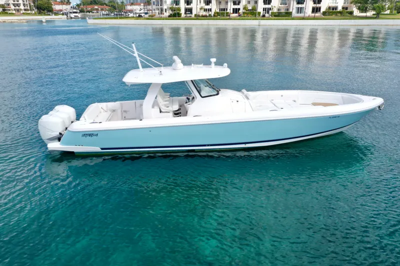 Slide: The Image of 2022 Intrepid 407 Nomad SE boat on clear blue water near waterfront buildings. - 2